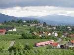 Mit Blick auf den Bodensee, die im Dunst liegenden �sterreichischen Berge und die herannahenden Regenwolken wurde vom Hermannsberg bei Lindau-Bodolz am 15.05.2011 RE 3994 fotografiert, der von Lindau �ber Kempten nach Ulm f�hrt.
